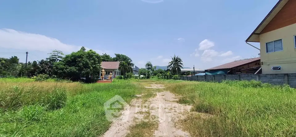 Expansive land plot with lush greenery and clear blue sky, ideal for development opportunities.
