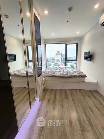 Modern bedroom with city view, featuring sleek flooring and built-in storage under the bed.