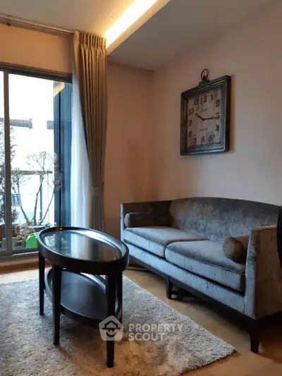 Chic living room with elegant sofa and stylish clock, featuring a cozy rug and natural light from large windows.