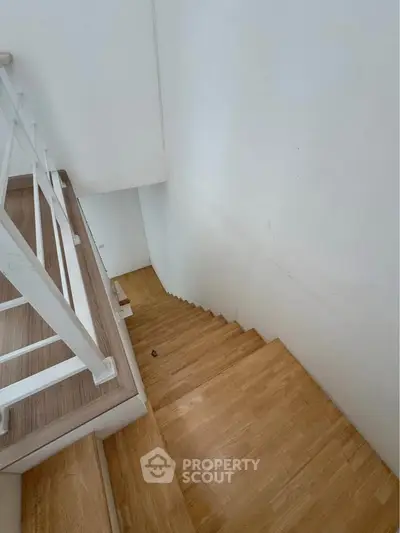 Modern wooden staircase with sleek white railing in a contemporary home interior.