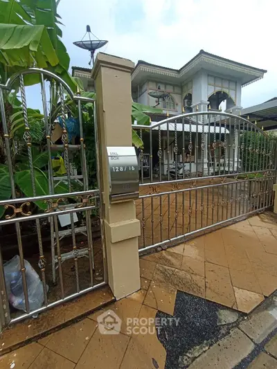 Elegant gated entrance of a luxurious home with manicured garden and modern architecture.