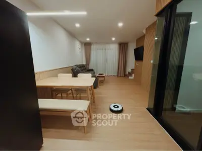 Modern living room with sleek furniture and robotic vacuum, featuring open layout and cozy ambiance.