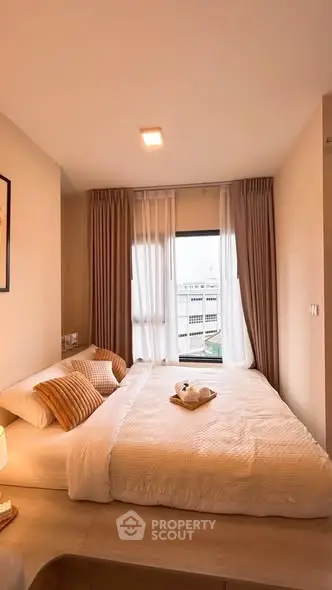 Cozy bedroom with large window and modern decor, offering a serene urban view.