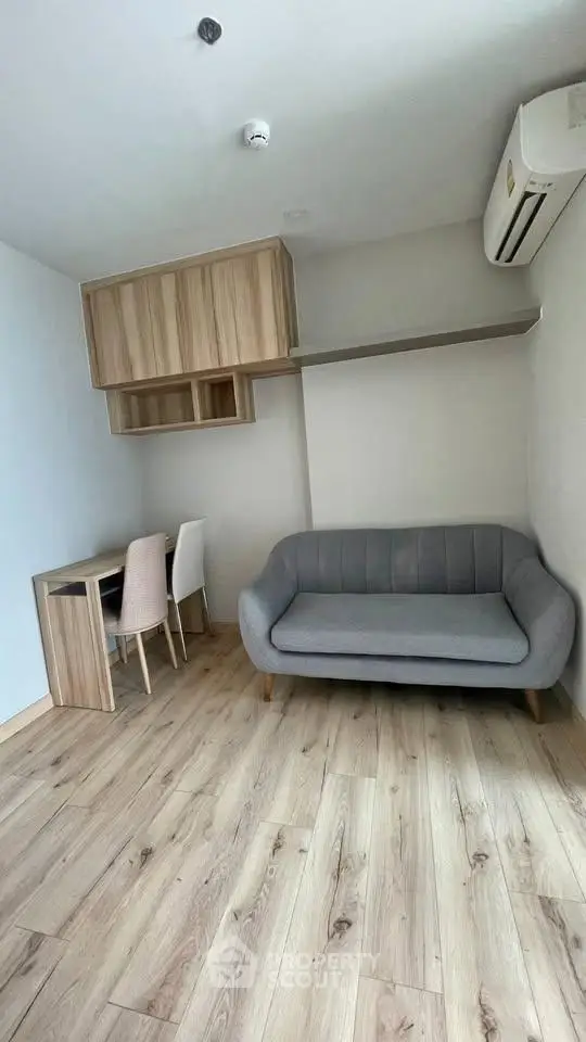 Modern living room with wooden flooring, stylish sofa, and compact workspace.
