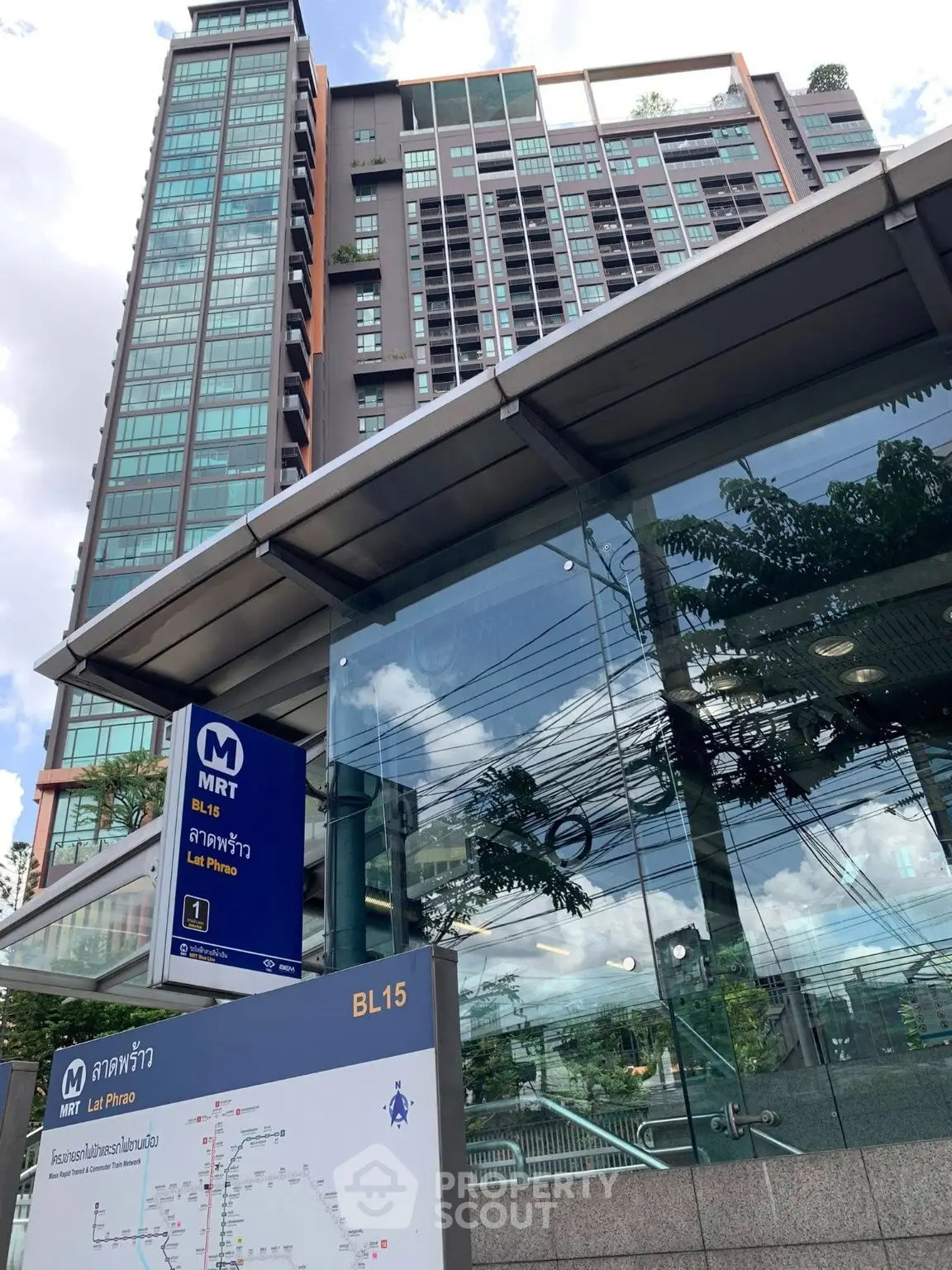 Modern high-rise building near MRT station with glass facade and urban surroundings.
