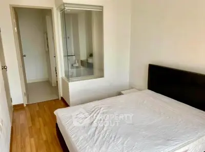 Modern bedroom with ensuite bathroom and wooden flooring in a stylish apartment.