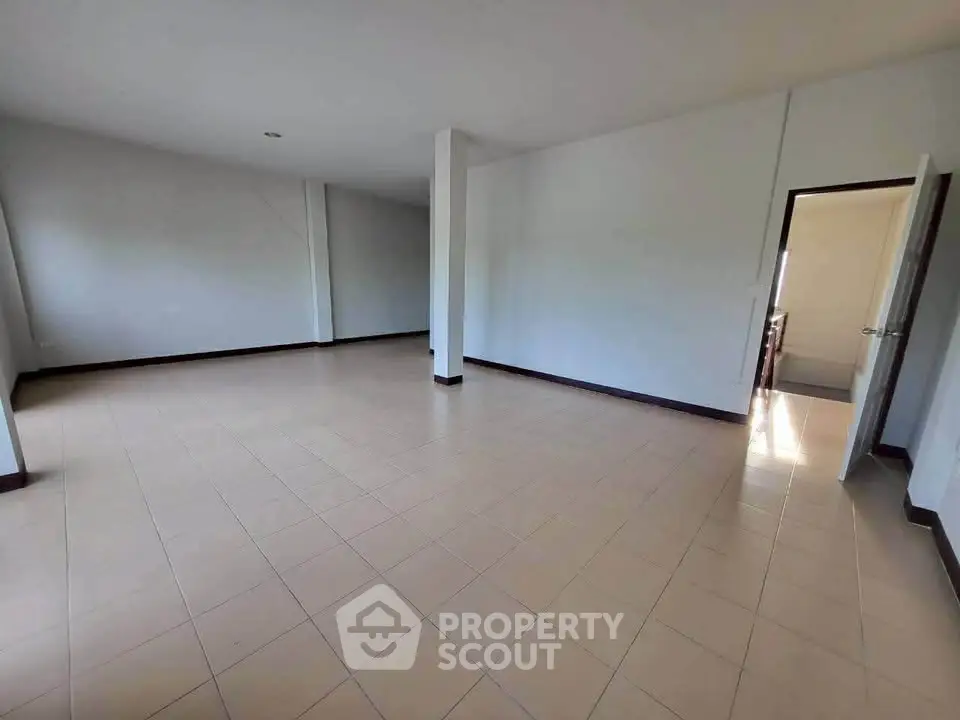 Spacious empty room with tiled flooring and open doorway, ideal for customization.