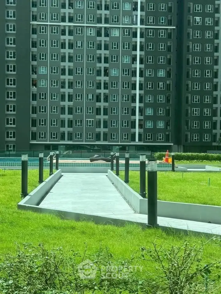 Modern apartment building with lush green lawn and pathway, ideal for urban living.