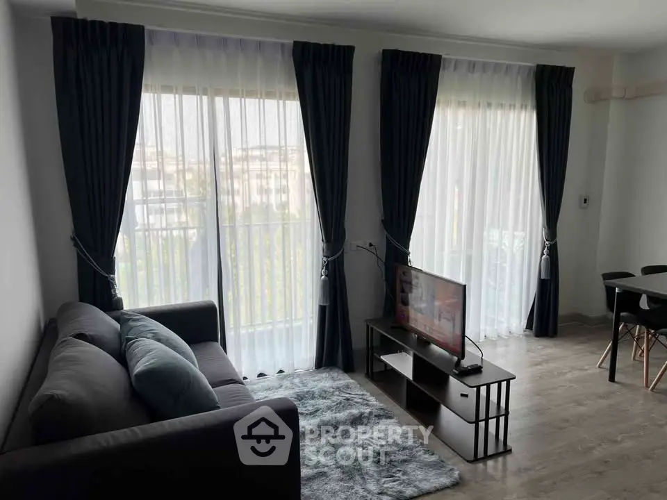 Modern living room with large windows, stylish curtains, and cozy seating area.