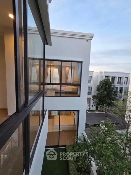 Modern apartment building with large windows and lush greenery, showcasing contemporary architecture and serene surroundings.