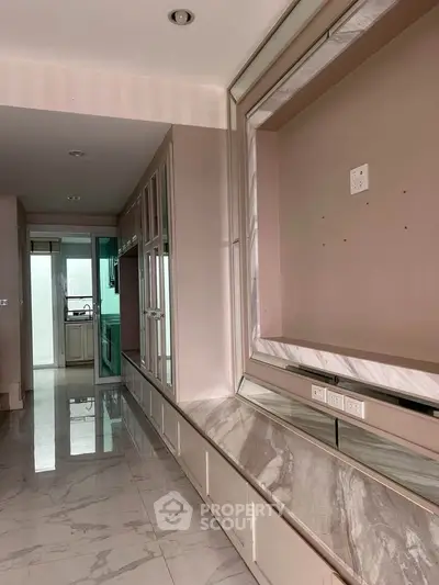 Spacious modern hallway with marble flooring and built-in storage, leading to a sleek kitchen.