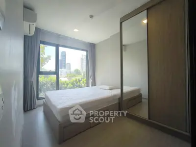 Modern bedroom with city view, featuring large window and mirrored wardrobe.