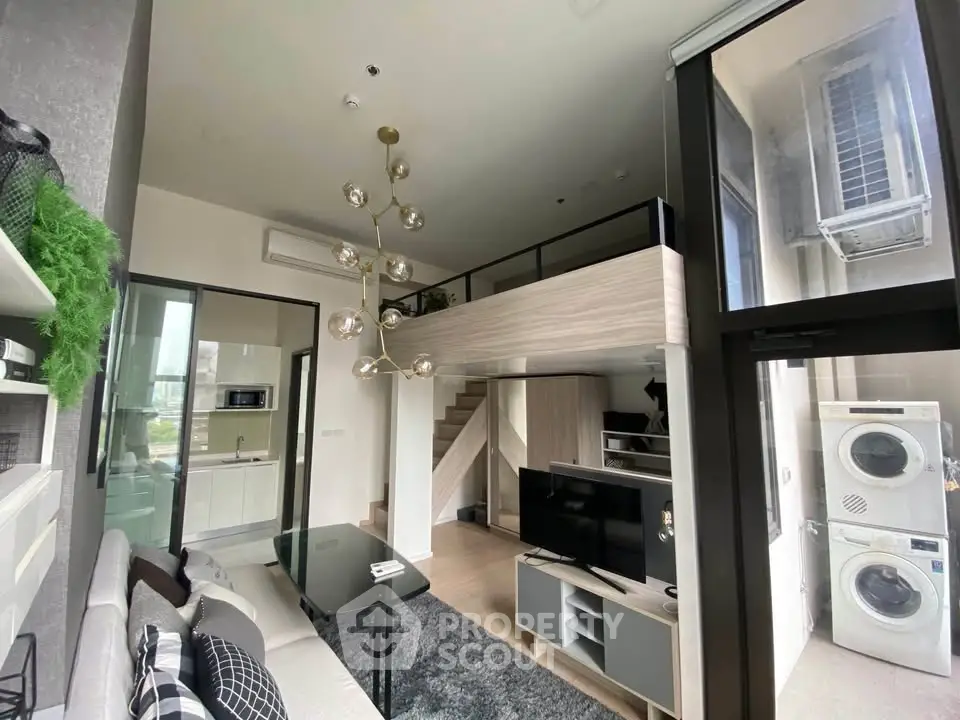 Modern loft apartment with high ceilings, stylish decor, and a compact kitchen featuring a washing machine.