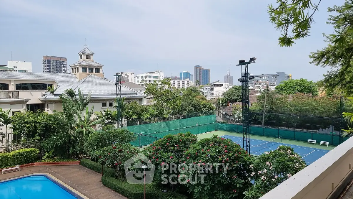Luxurious urban residence with tennis court and pool, surrounded by lush greenery and city skyline views.