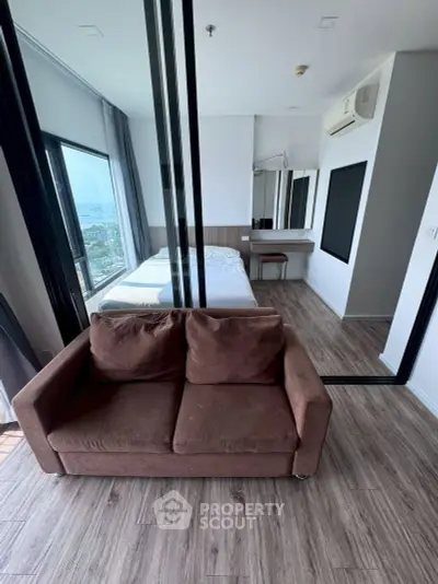 Modern studio apartment with large windows and stylish furnishings, offering a stunning city view.