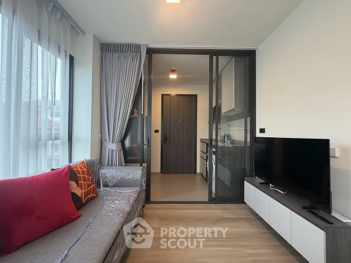 Modern living room with sleek kitchen, large windows, and stylish decor in a contemporary apartment.
