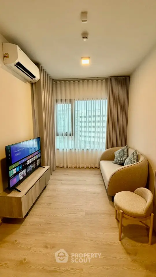 Modern living room with sleek TV setup and cozy seating in a bright apartment.