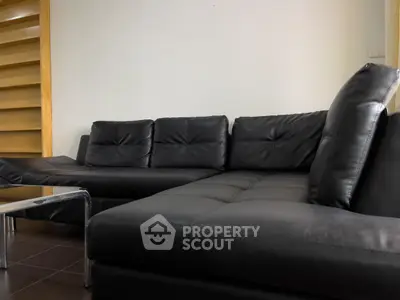 Modern living room with sleek black leather sectional sofa and minimalist design.