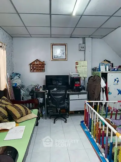 Cozy living room with office setup and baby play area, featuring a comfortable sofa and organized workspace.