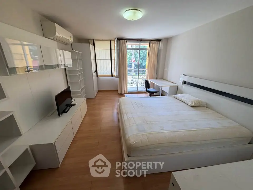 Spacious modern bedroom with balcony and stylish furniture in a bright apartment.