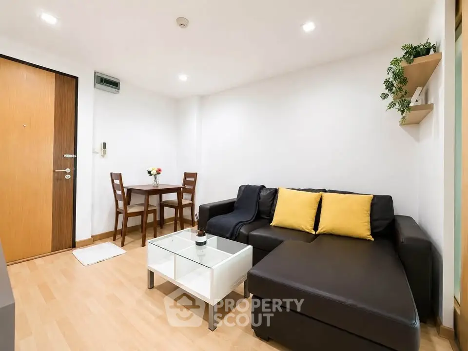 Modern living room with sleek black sofa and dining area in cozy apartment.