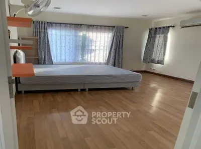 Spacious bedroom with large window and wooden flooring