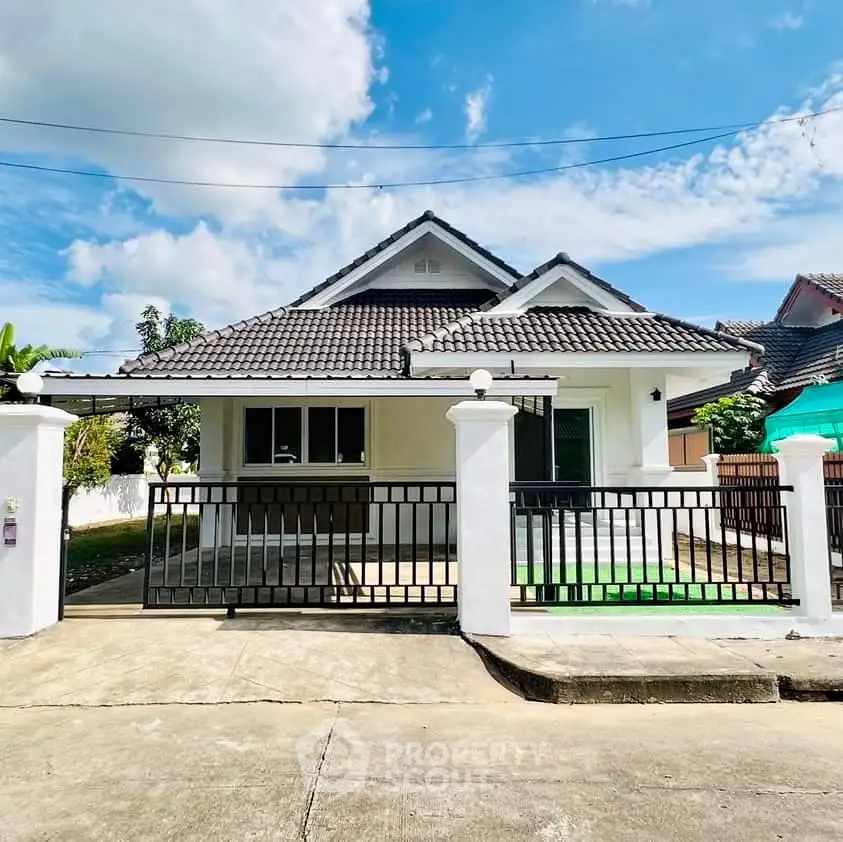 Charming single-story house with a gated entrance and tiled roof under a clear blue sky.