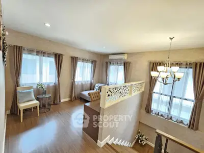 Elegant living room with stylish decor and natural light, featuring a cozy seating area and modern staircase.