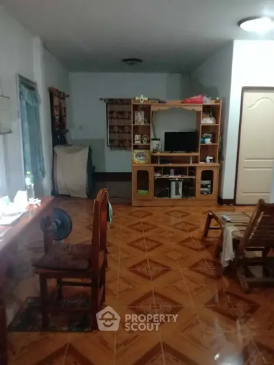 Spacious living room with wooden flooring and entertainment center, ideal for family gatherings.