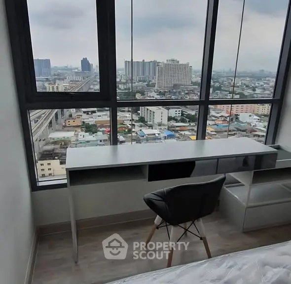 Modern high-rise apartment with stunning city view from bedroom window, featuring sleek desk and chair.