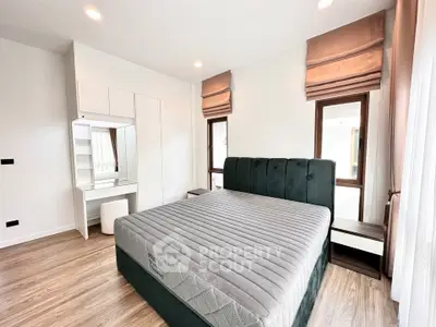 Spacious bedroom with modern design, featuring a large bed and elegant window treatments.