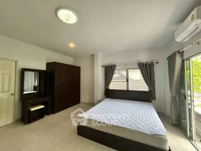 Spacious bedroom with modern furniture and large window for natural light.