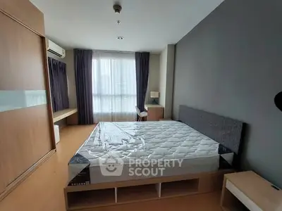 Spacious bedroom with modern furnishings and large window for natural light.