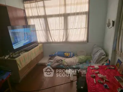 Cozy bedroom with natural light, TV, and minimalist decor for a comfortable living space.