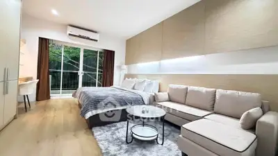 Modern bedroom with cozy sofa and large window overlooking greenery, perfect for relaxation.