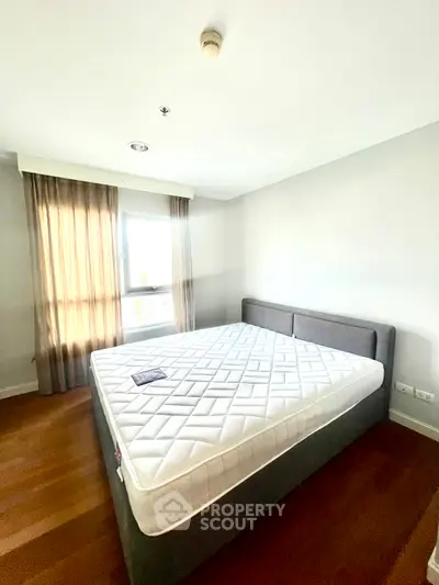 Spacious bedroom with large window and modern bed frame, perfect for relaxation.