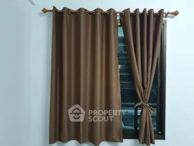 Elegant brown curtains in a modern apartment window, adding warmth and privacy.