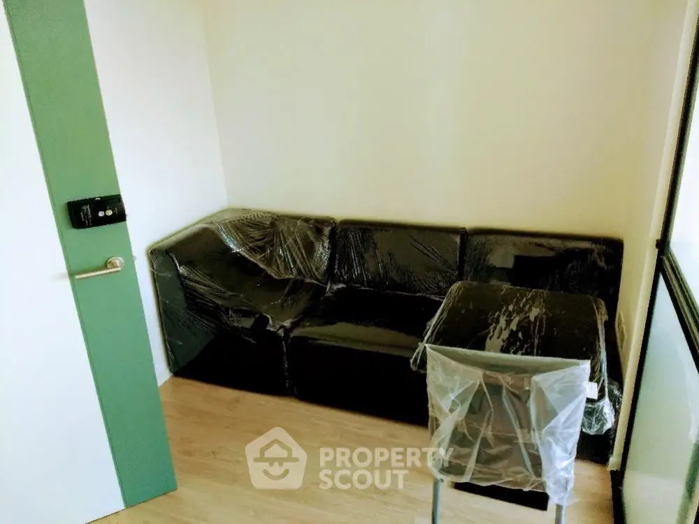 Cozy small living room with plastic-covered furniture and wooden flooring