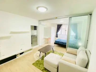 Modern open-plan living room with cozy sofa and bedroom view