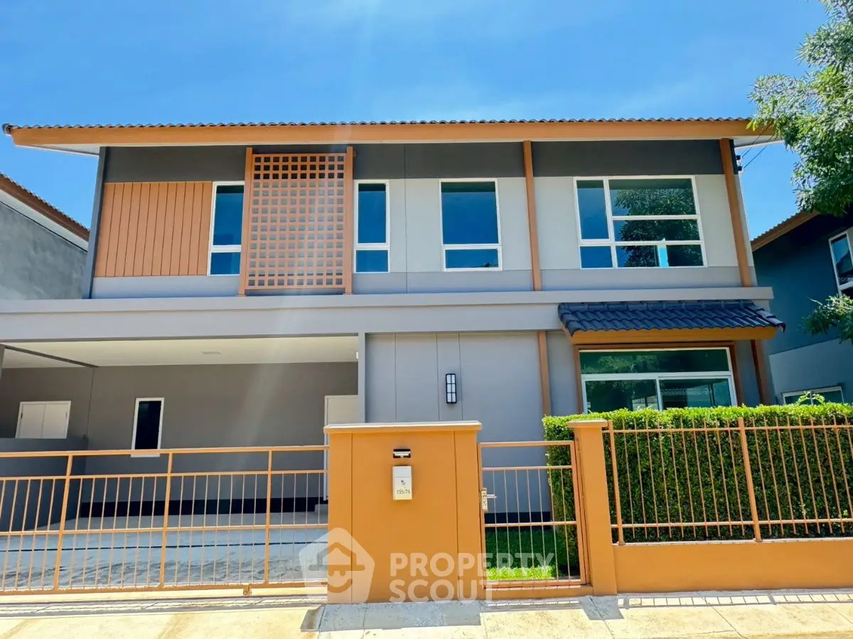 Modern two-story house with sleek design and spacious driveway under clear blue sky.