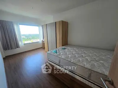 Spacious bedroom with large window and wooden flooring offering scenic views.