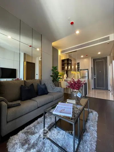 Modern living room with cozy sofa, stylish decor, and open kitchen layout in a chic apartment.