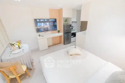 Modern studio apartment with cozy bed, dining area, and sleek kitchen appliances.