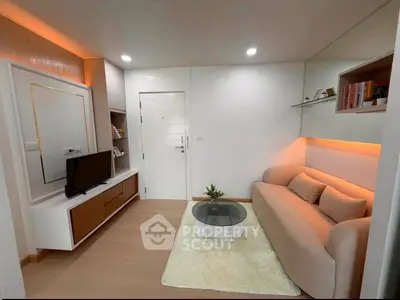 Modern living room with cozy sofa, sleek TV unit, and ambient lighting in a stylish apartment.
