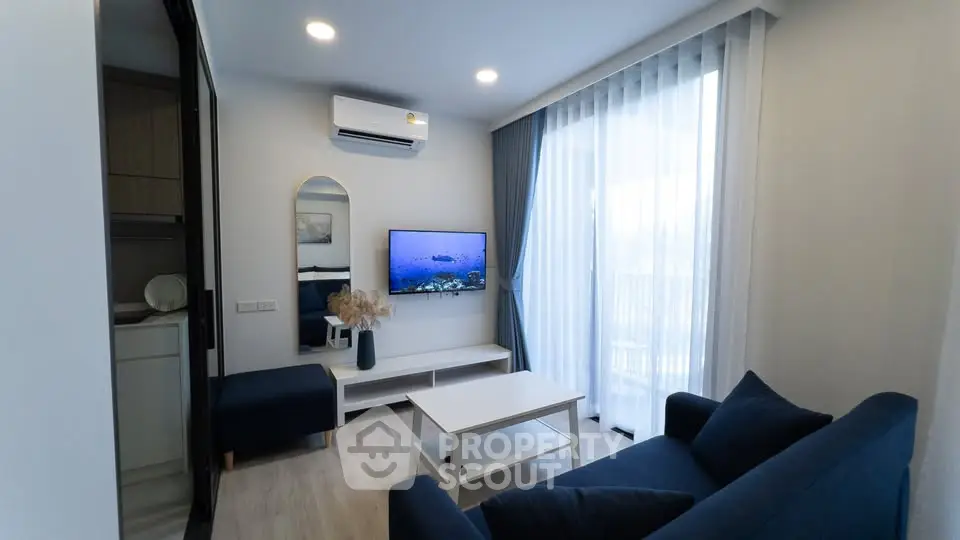 Modern living room with sleek furniture and natural light, featuring a wall-mounted TV and stylish decor.