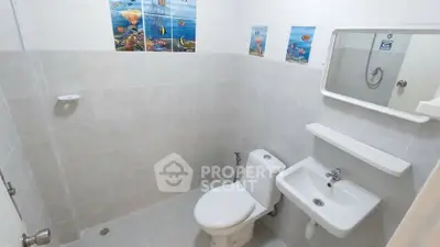 Compact bathroom with white tiles and ocean-themed wall decor