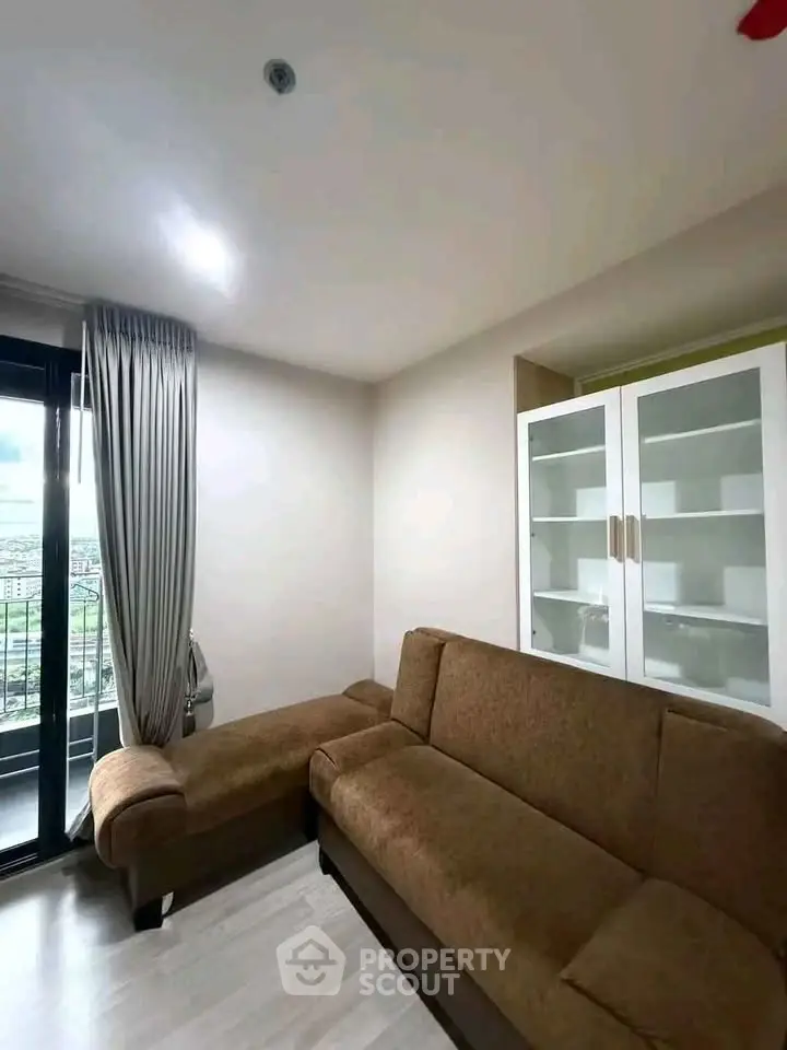 Modern living room with cozy brown sofa and glass cabinet, featuring a balcony view.