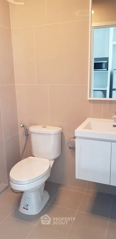 Modern bathroom with sleek fixtures and neutral tiles, featuring a contemporary toilet and vanity.