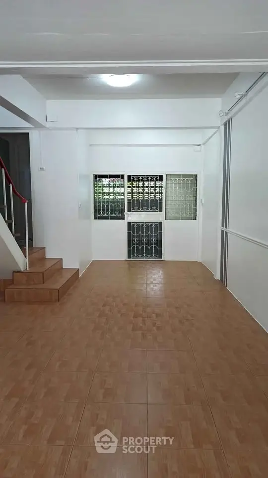 Spacious interior with tiled flooring and staircase, ideal for versatile living space.