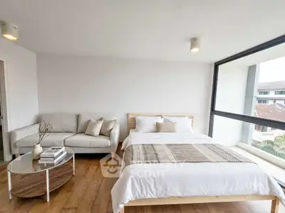 Spacious bedroom with modern decor and large window offering natural light